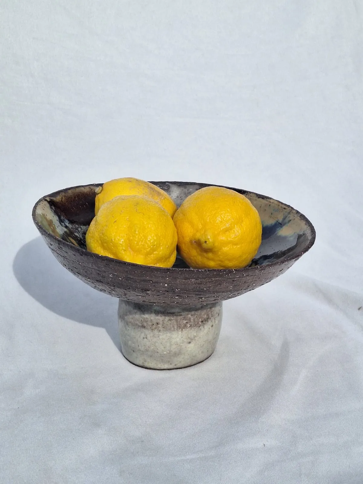 The fruit bowl — A footed bowl in dark stoneware with a pooled cobalt and amber interior.